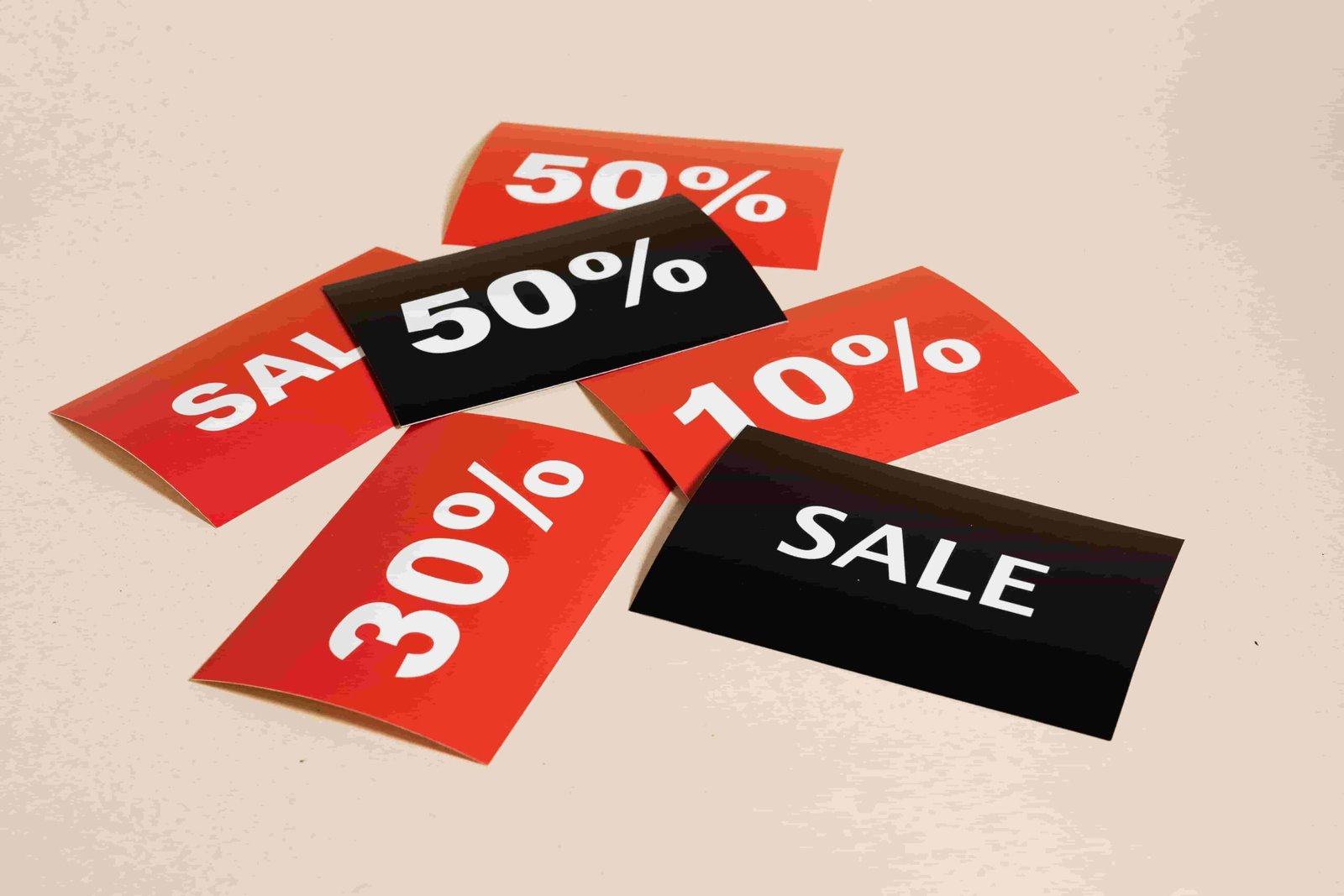 A scattered arrangement of red and black sale tags, displaying various discount percentages (50%, 50%, 30%, and 10%) and the word "SALE," lies against a neutral background. Just like finding the right insurance policy, these tags offer diverse savings to consider.