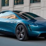 A sleek, modern Tesla Model Q 2025 with a glossy blue finish is parked on a city street. This electric car features a streamlined design with tinted windows and black wheels. An urban building stands majestically in the background.