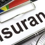 A clipboard holds a document labeled "Insurance" in large letters—perhaps Special Event Insurance—with a pen, glasses, and part of a calculator visible nearby.